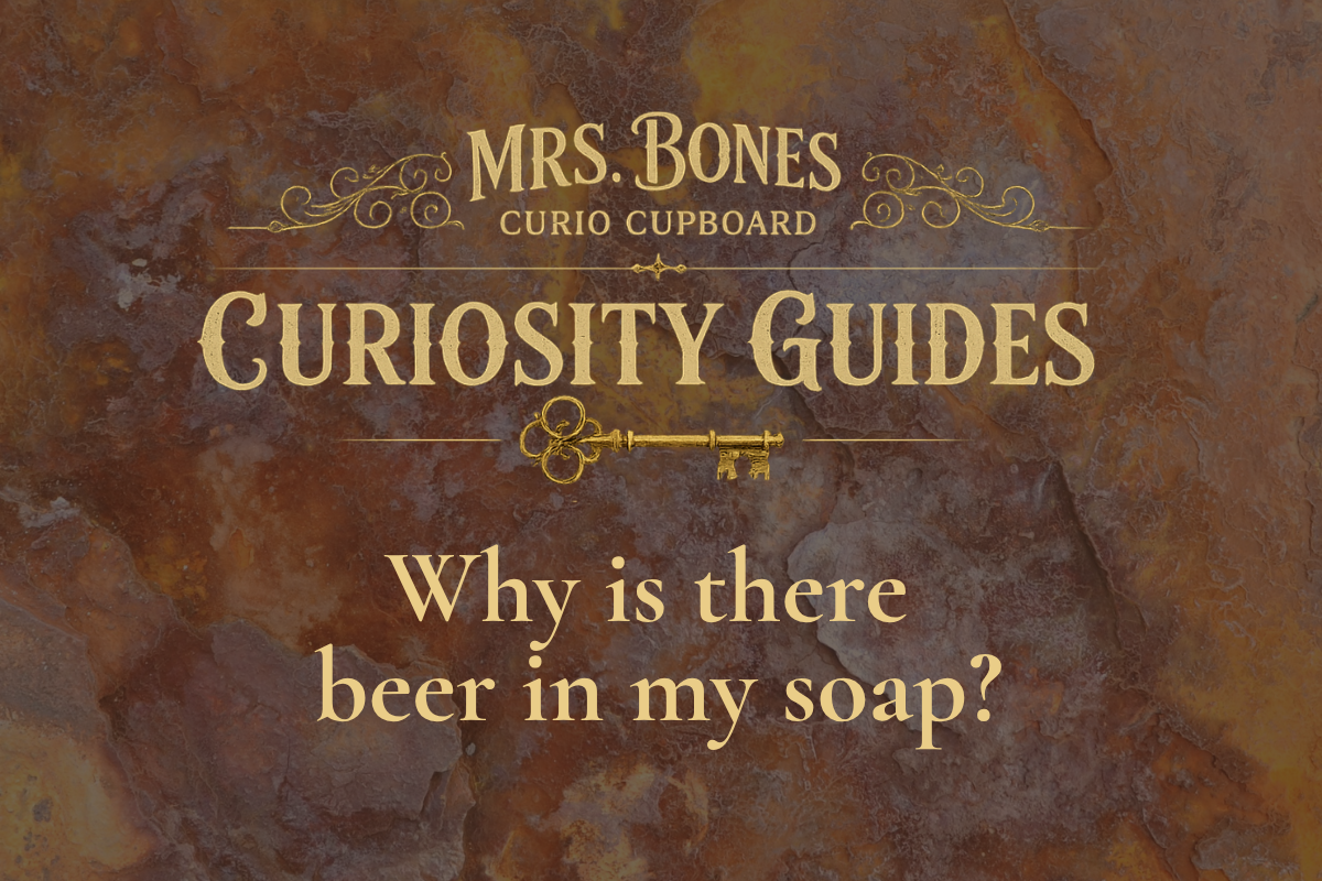 Mrs. Bones Curio Cupboard Curiosity Guide cover asking “Why is there beer in my soap?” on a brown and amber marbled background with antique gold lettering and skeleton key.