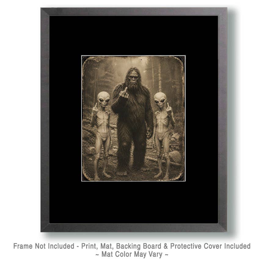 A framed art print featuring a sepia-toned illustration of a Bigfoot-like figure standing between two alien-like creatures, shown with a black mat and dark frame on a white background. Text below notes that the frame is not included and the print, mat, backing board, and protective cover are included.