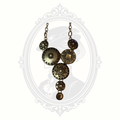 Antiqued brass statement necklace with layered medallions and floral-inspired detailing displayed against a gothic cameo background.