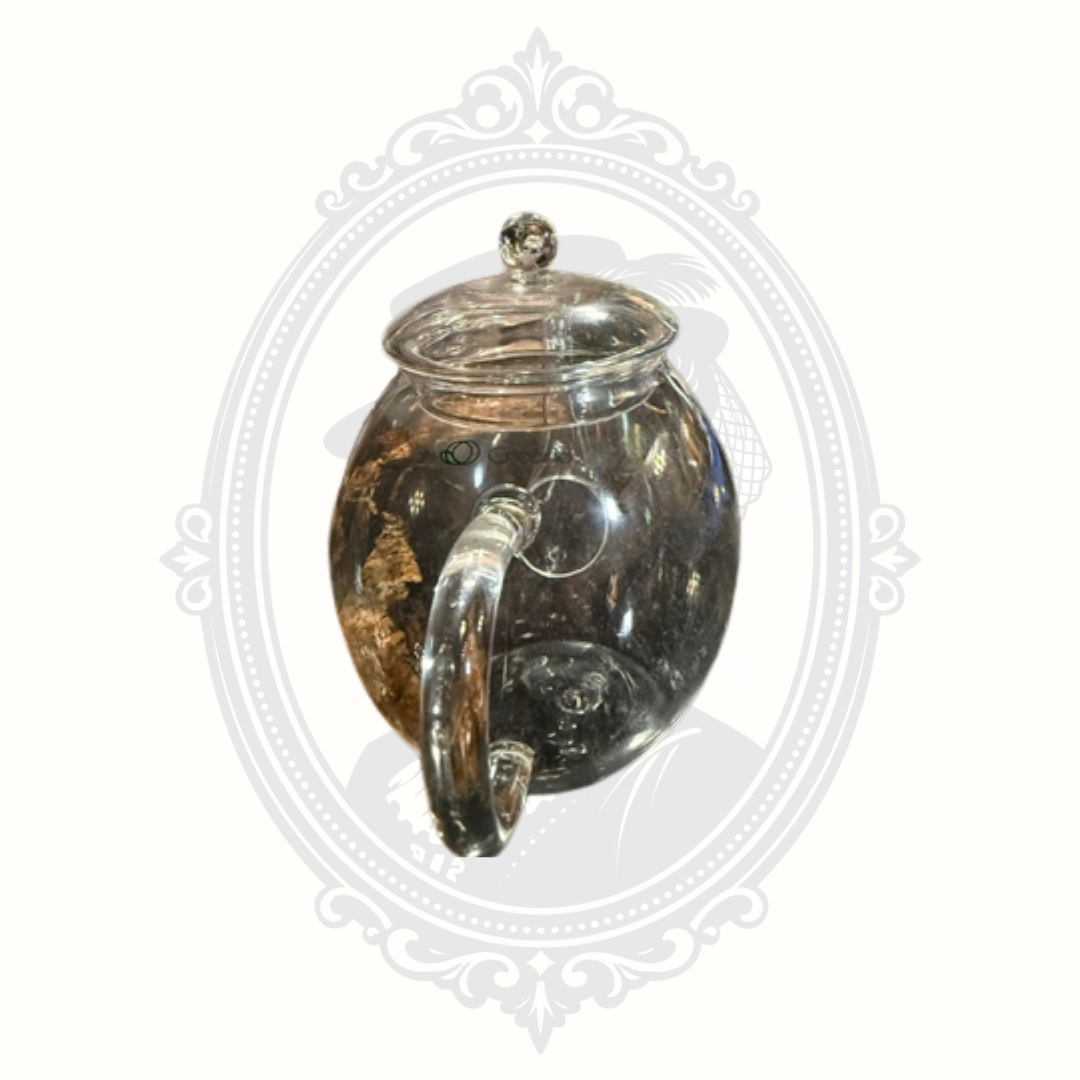 Rear angle view of borosilicate glass teapot displaying curved handle and rounded silhouette against decorative gray background.