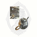 Clear Creano borosilicate glass teapot with matching lid photographed from above on a gray Mrs. Bones Curio Cupboard background with logo inset detail.