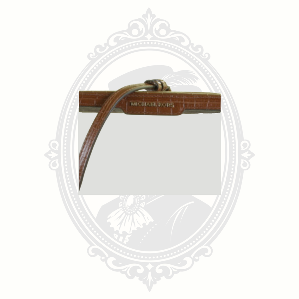 Close-up view of Michael Kors logo on brown croc-embossed trim of clear stadium bag.