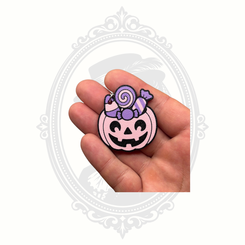 Pink Candy Pumpkin keychain shown in the palm of a hand to demonstrate its collectible size and detailed candy-themed Halloween design.