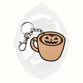 Pumpkin Spice Coffee Cup Halloween keychain featuring a beige coffee mug topped with jack-o'-lantern pumpkin latte art, complete with a metal keyring and lobster clasp.