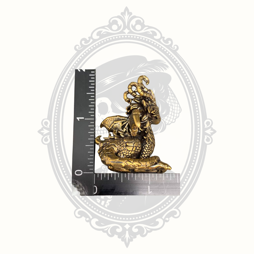 Mini brass dragon figurine beside ruler showing approximate size.