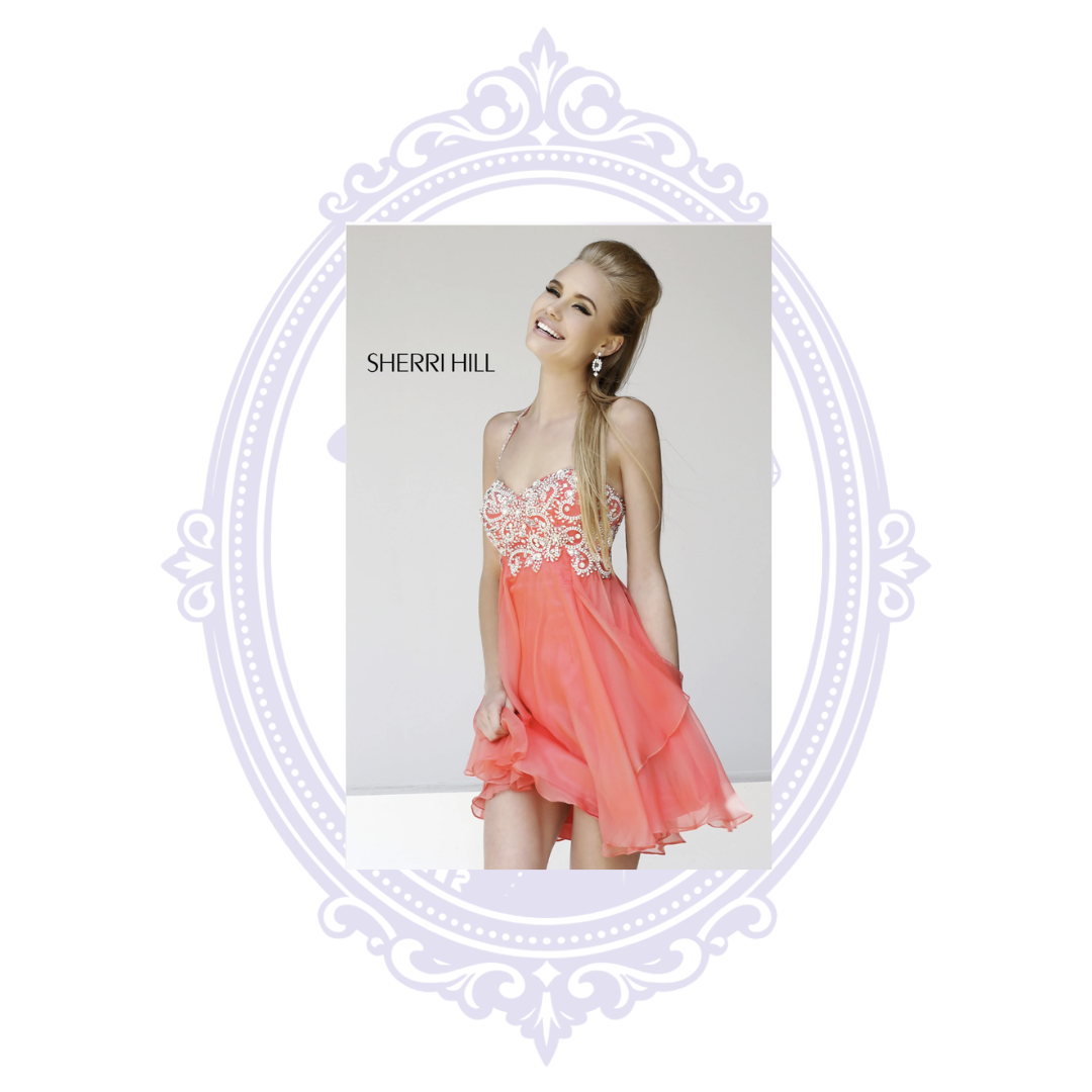 Official Sherri Hill model photo showing Style 3878 in the Coral colorway, featuring a sparkling rhinestone- and bead-embellished sweetheart bodice, slender jeweled halter strap, and flowing short chiffon skirt. The full original fashion photograph is centered within a pale lavender ornamental frame on a white background.