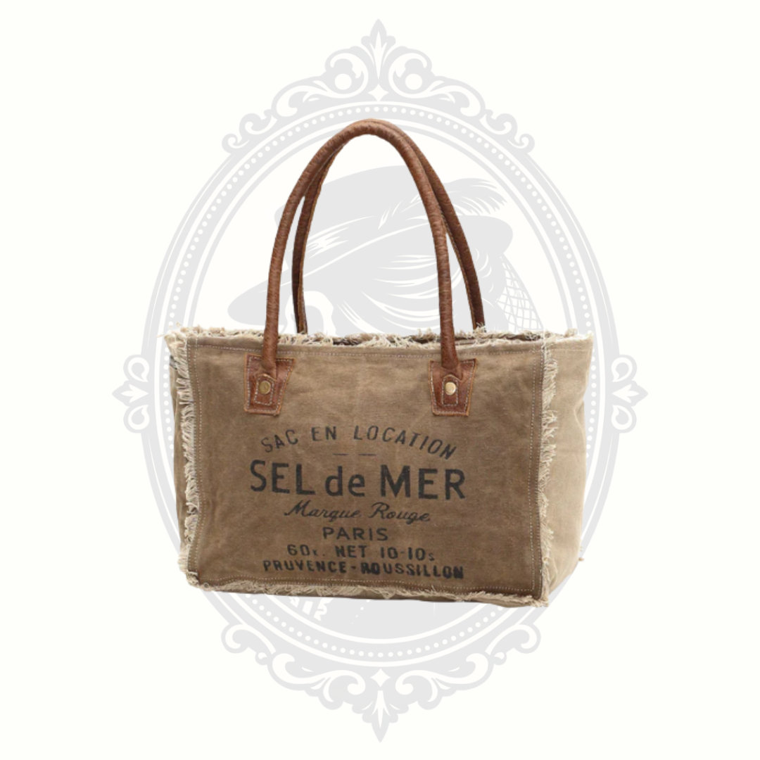 Brown tote bag with leather handles and visible branding on a white background