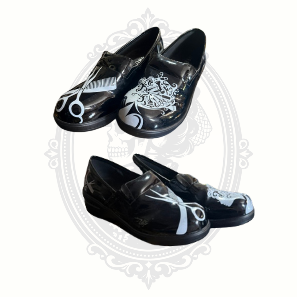 Black glossy slip-on shoes featuring oversized white scissors, comb, and hairstylist artwork shown from front and angled views.