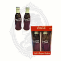 Vintage Coca-Cola bottle-shaped ceramic salt and pepper shakers displayed beside the original red Coca-Cola branded packaging.