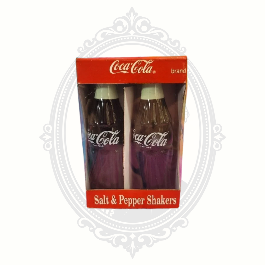 Vintage 1996 Coca-Cola ceramic salt and pepper shaker set in original red Coca-Cola branded box with bottle-shaped shaker design.