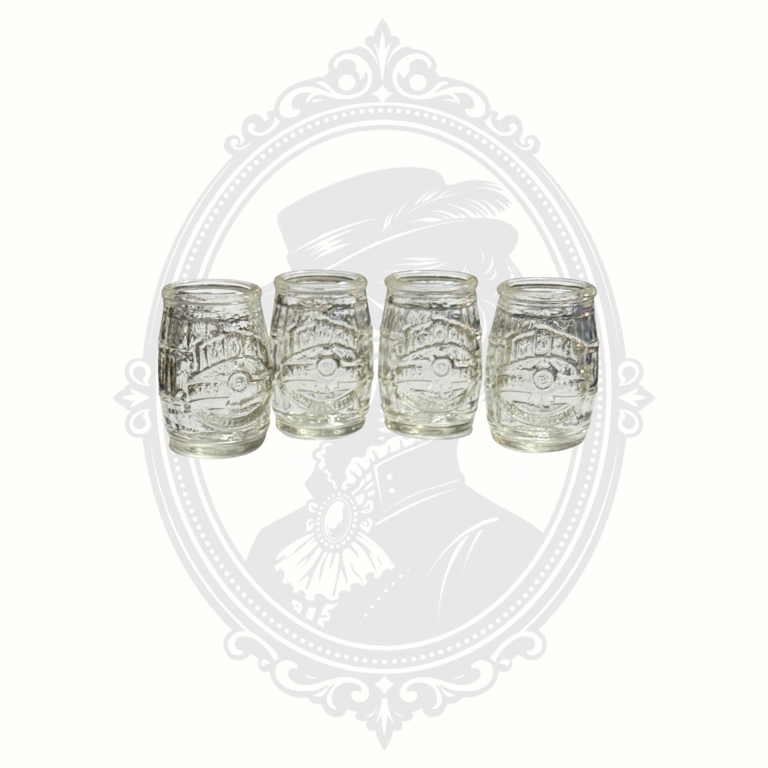 Set of four vintage clear glass Jim Beam barrel-shaped shot glasses with embossed logo and textured whiskey barrel design.