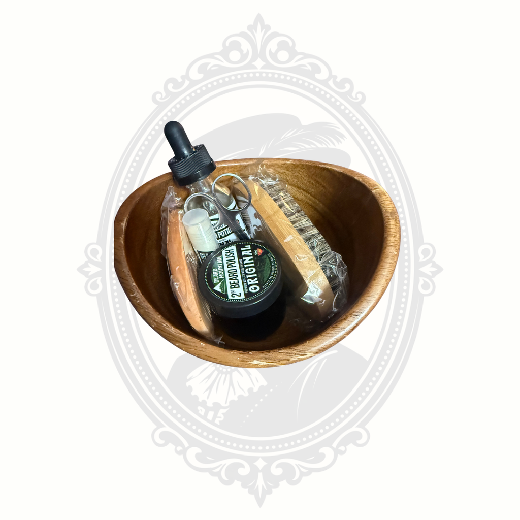 Top view of men’s beard grooming kit in wooden bowl showing beard oil, balm, comb, brush, and scissors