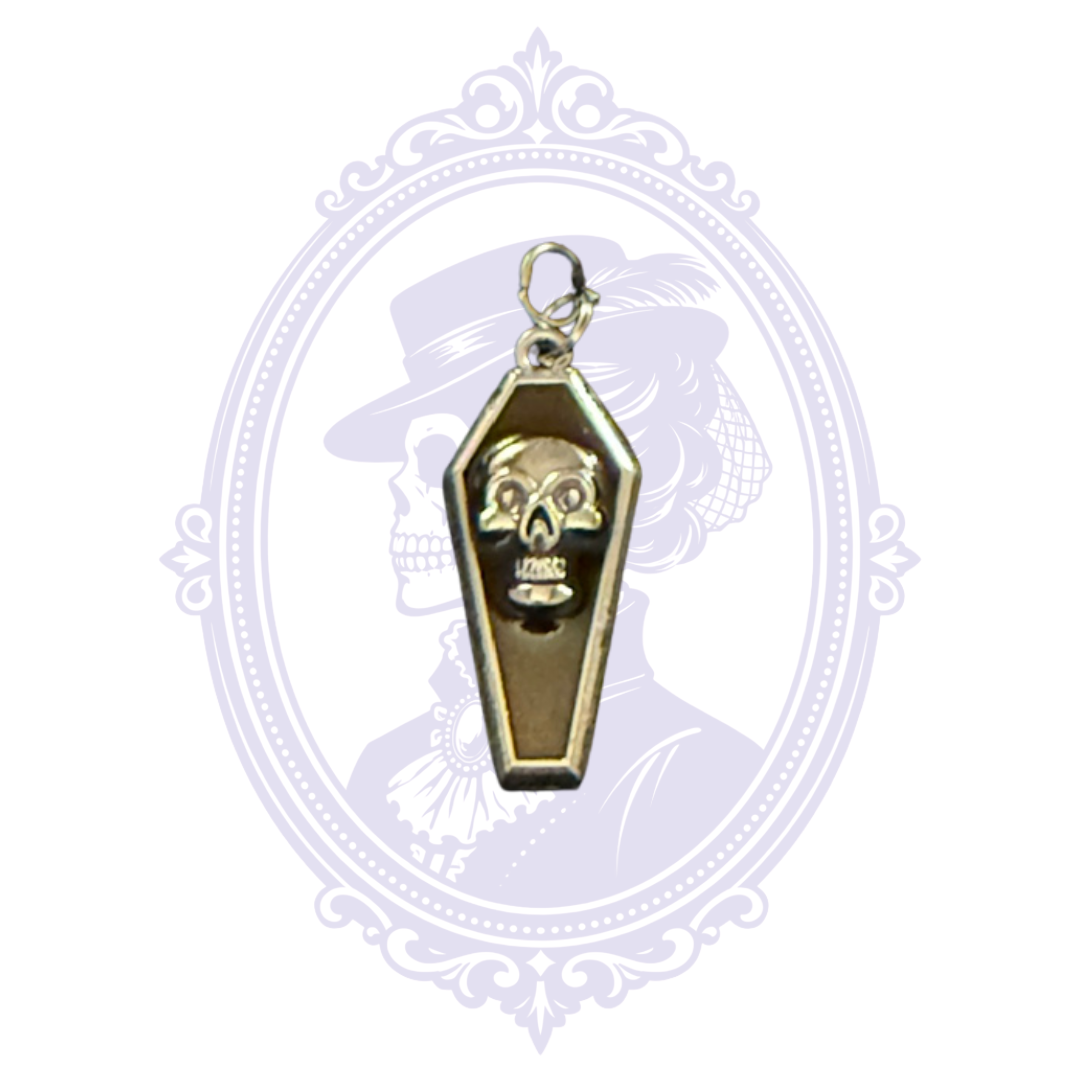 Close-up of black coffin pendant with raised silver-tone skull and silver-tone border.