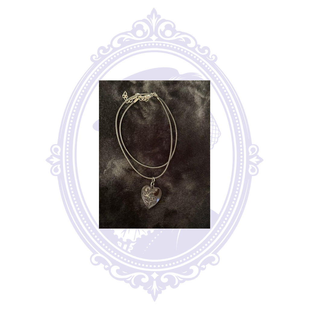 Black-on-black ornate heart pendant necklace with adjustable black cord and extender chain.