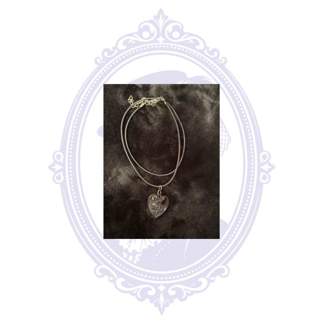 Black-on-black ornate heart pendant necklace with adjustable black cord and extender chain.