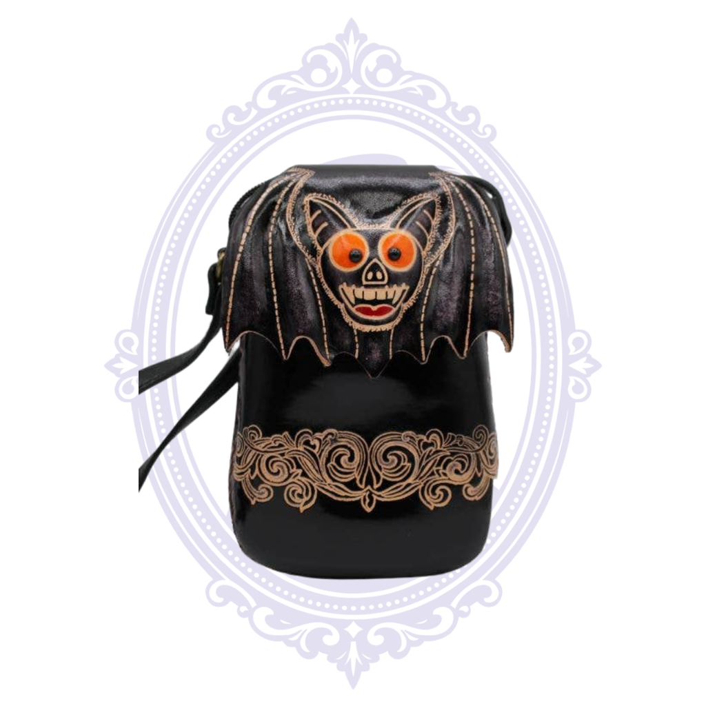 Black leather crossbody bag with dimensional bat face, orange eyes, and ornate tan scrollwork
