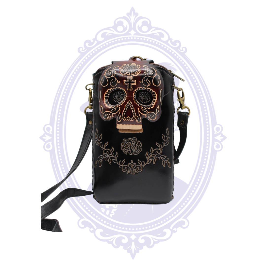 Front view of black genuine leather cell phone crossbody holder with dimensional sugar skull flap and ornate floral detailing.