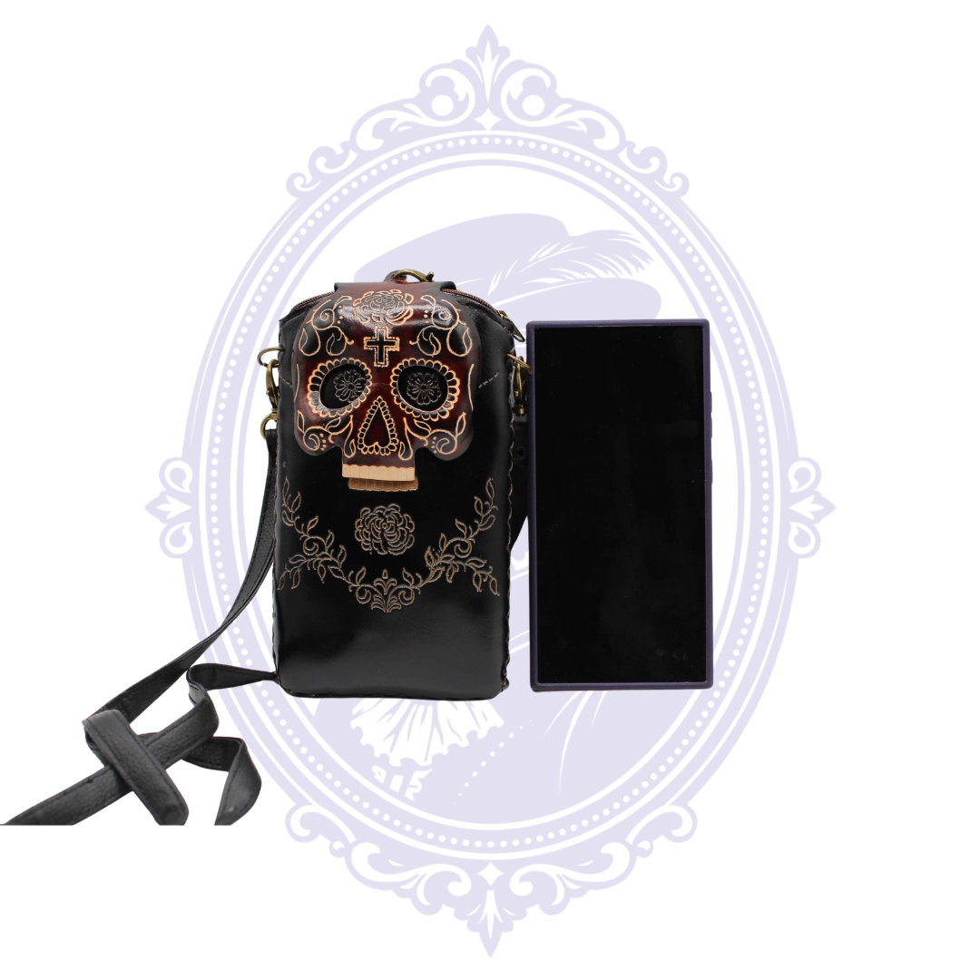 Black genuine leather sugar skull cell phone crossbody holder shown beside a card-sized object for scale.