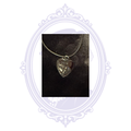 Black-on-black heart pendant with raised ornate scrollwork on a black cord necklace.