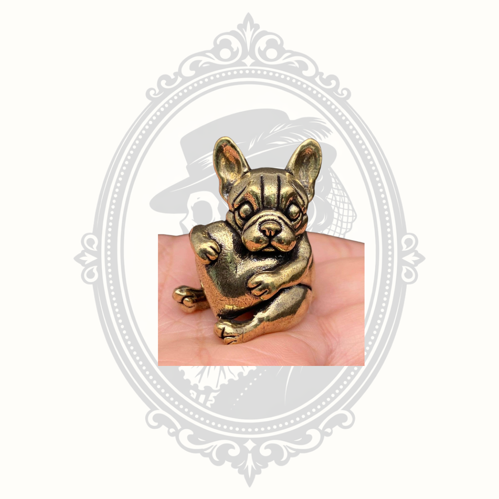 Miniature solid brass French Bulldog figurine hugging a heart displayed in hand for scale.