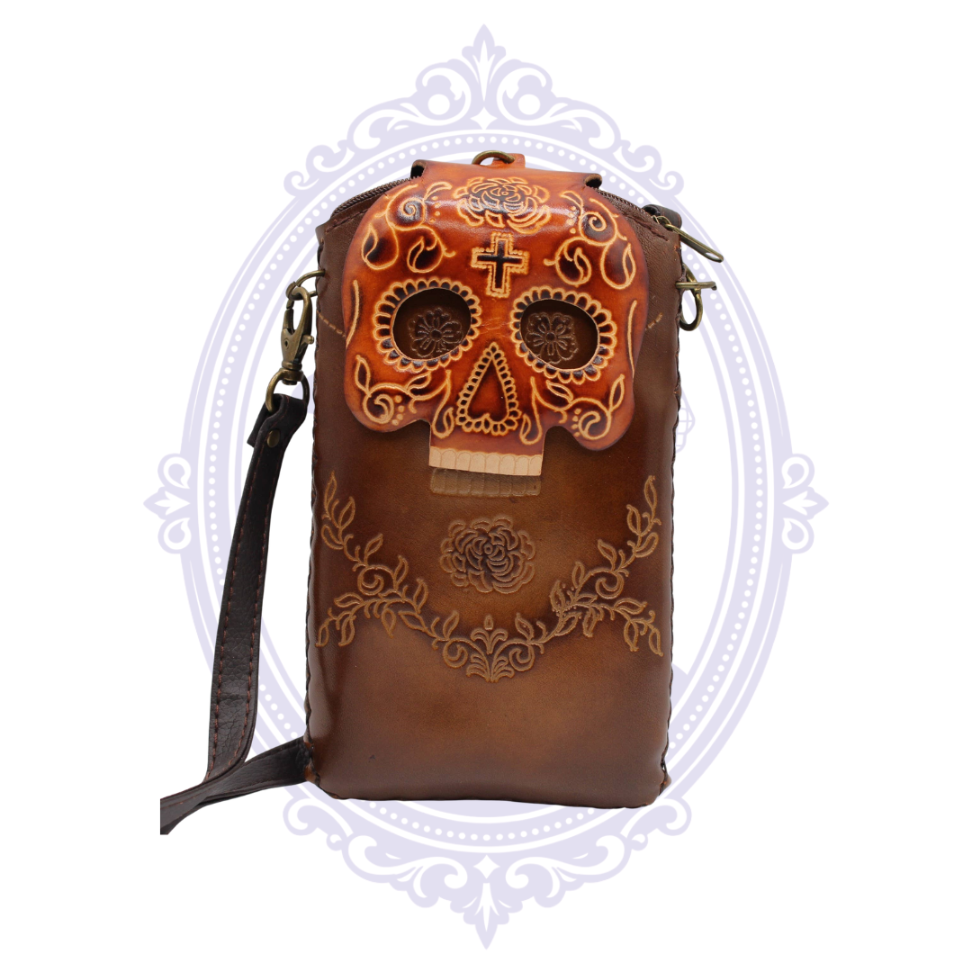 Front view of brown genuine leather cell phone crossbody holder with ornate sugar skull flap and floral detailing.