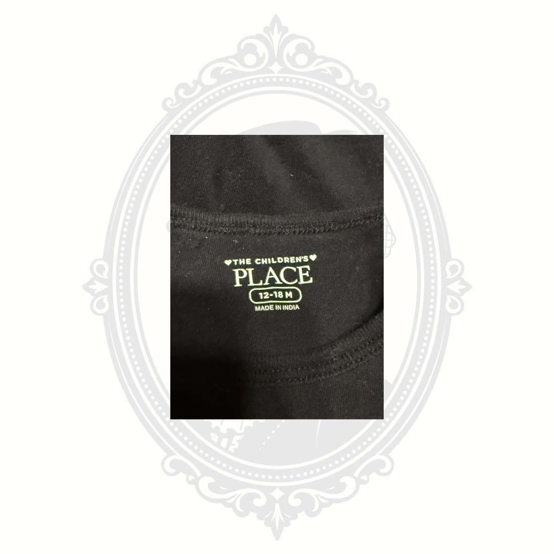Close-up of The Children’s Place size tag showing 12-18 months on black baby onesie.