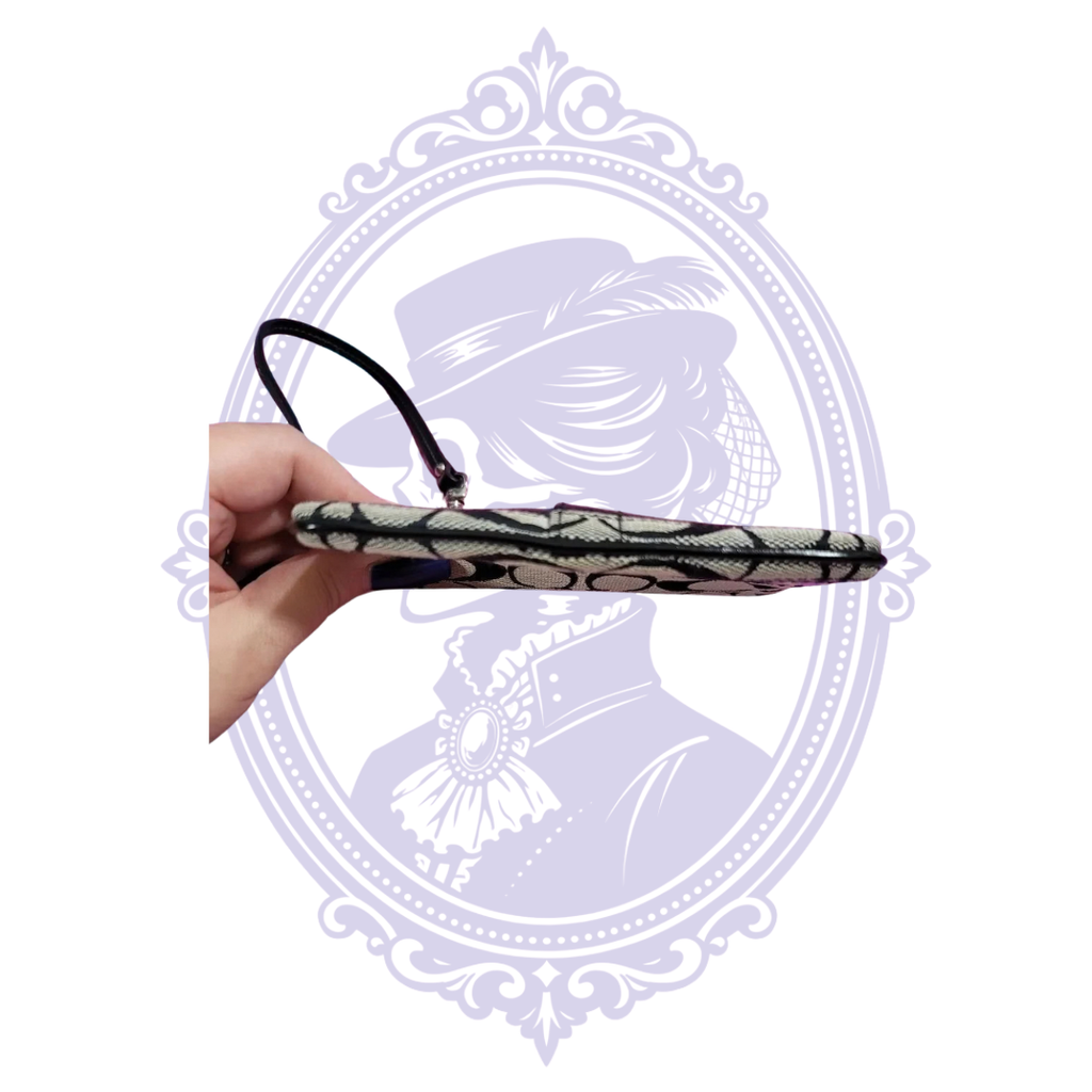 Coach wristlet side view with attached black leather wrist strap