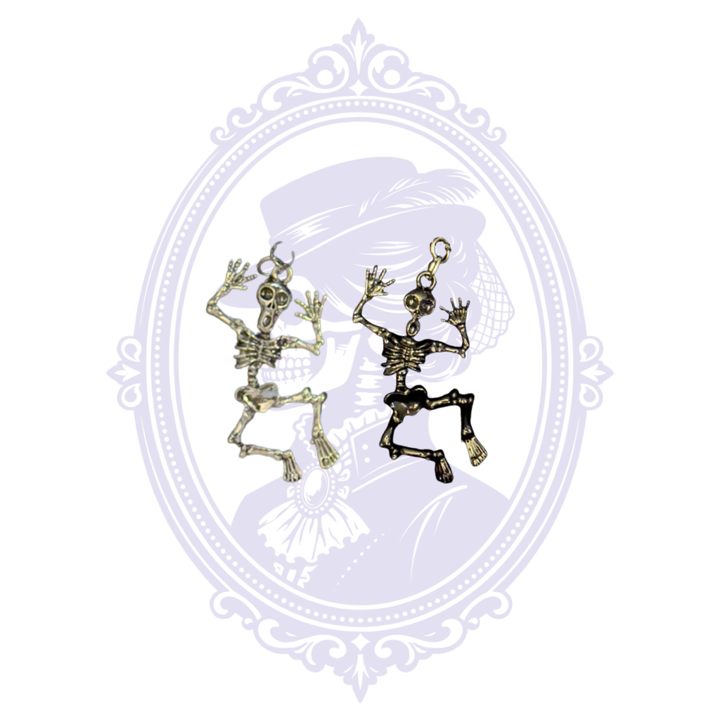 Silver-tone and black articulated skeleton pendants shown together, displaying the two available Cupboard Crafted necklace finishes.