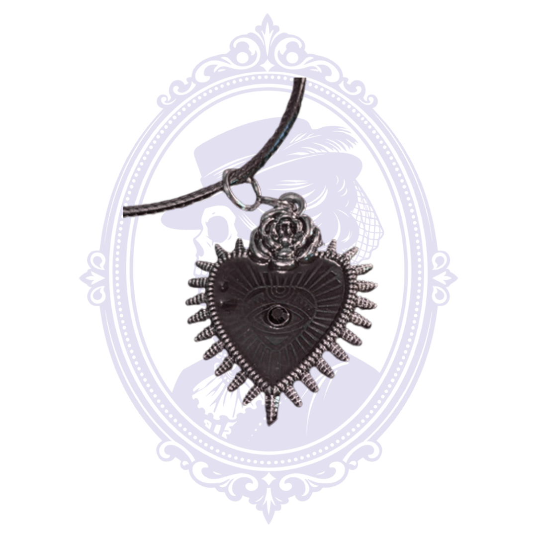 Close-up of black heart pendant showing raised eye, black center stone, rose and radiating details.
