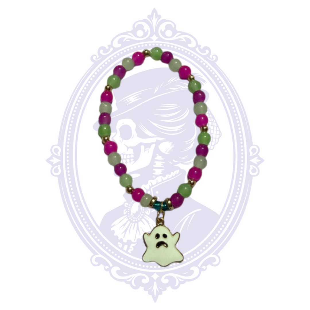 Purple and green glass bead stretch bracelet with gold-tone accents and pale ghost charm, shown in a rounded display.
