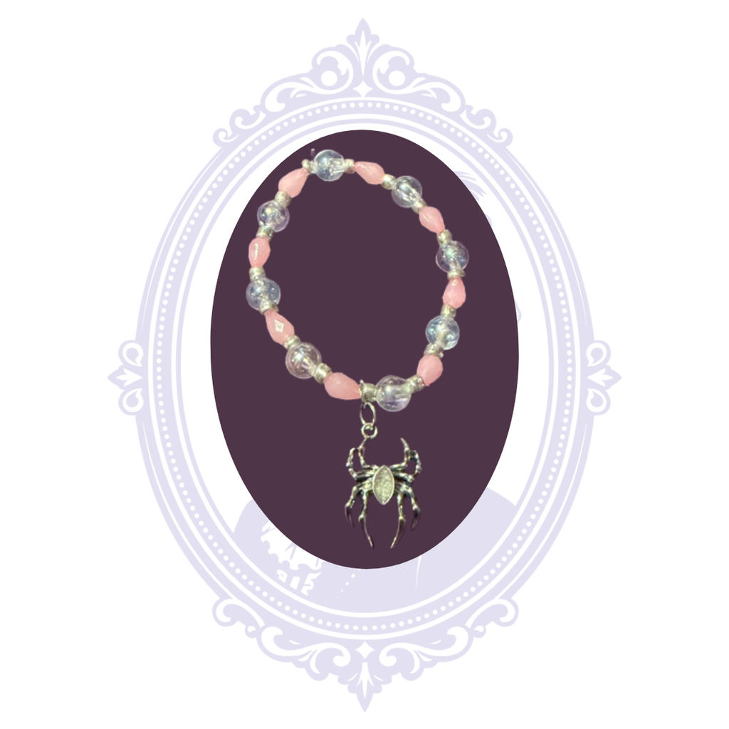 Full view of pink and iridescent beaded bracelet featuring silver-tone spacer beads and a dangling spider charm.