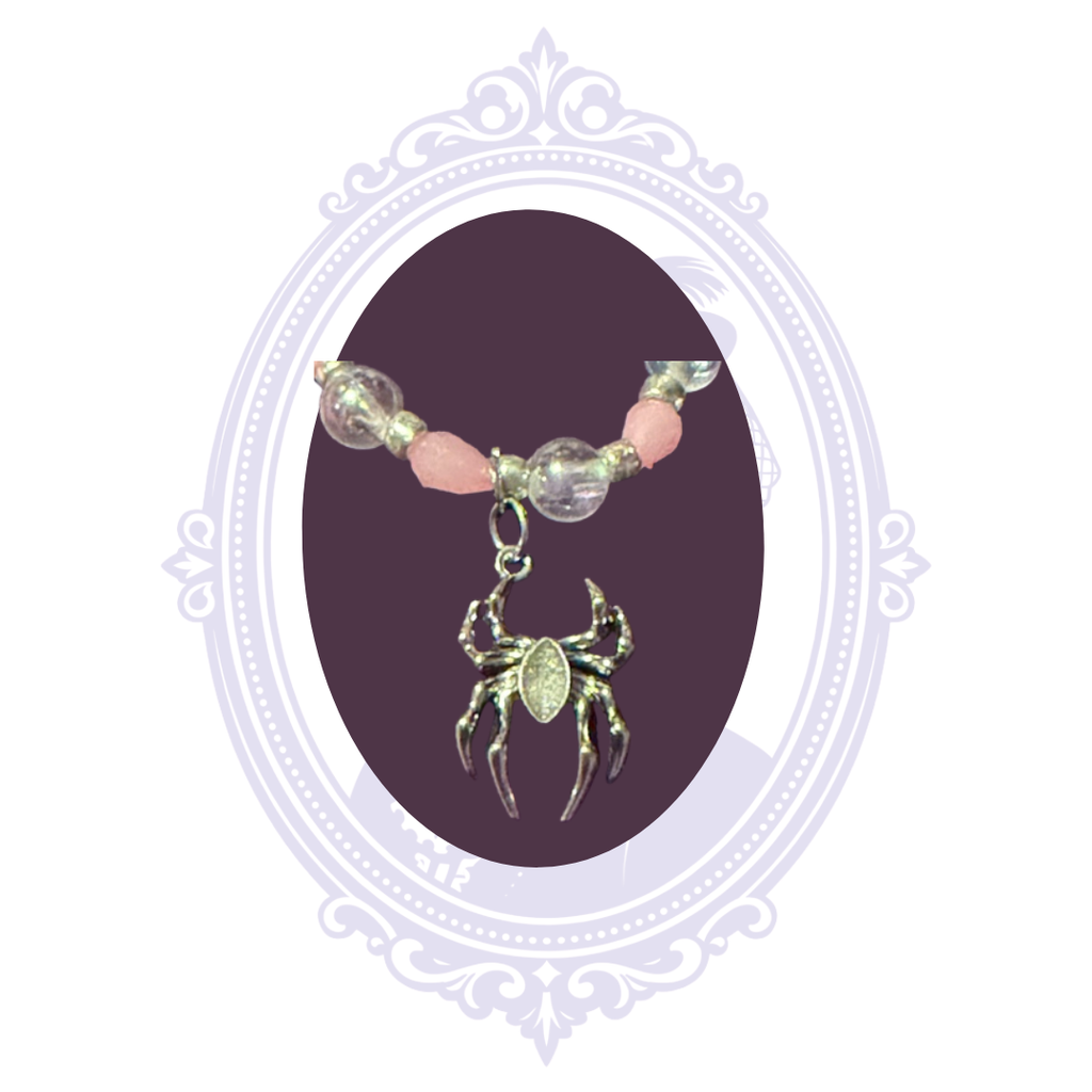 Close-up of the dimensional silver-tone spider charm on a pink and iridescent beaded bracelet.