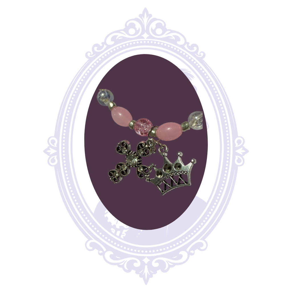 Detailed view of sparkling ornate cross and silver-tone crown charms with pink beads and silver-tone accents.