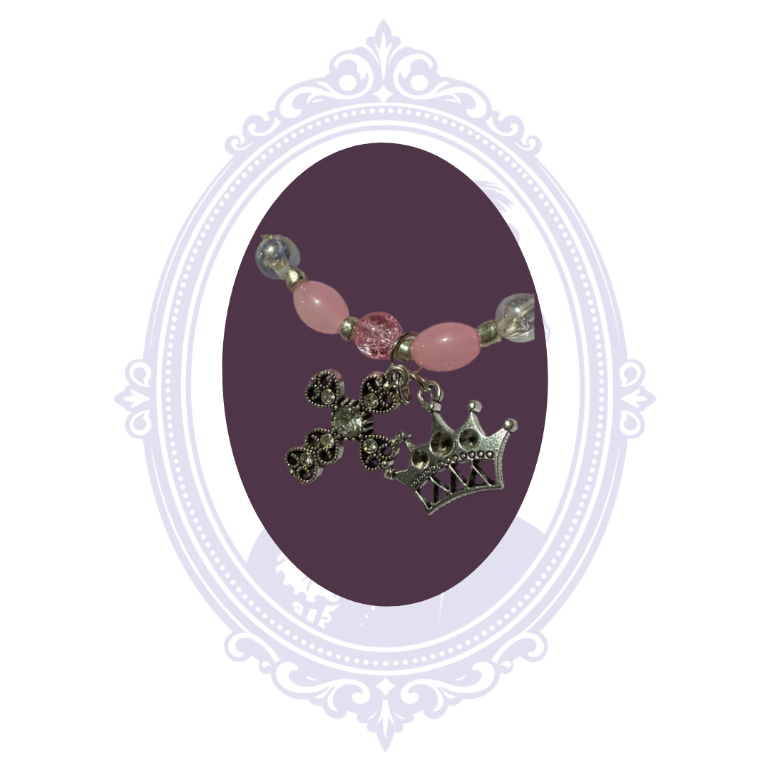 Detailed view of sparkling ornate cross and silver-tone crown charms with pink beads and silver-tone accents.