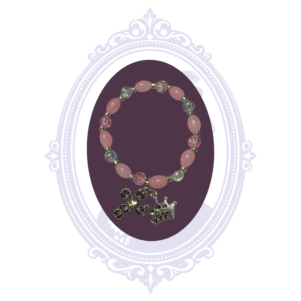 Full view of pink and clear beaded stretch bracelet with dangling cross and crown charms.