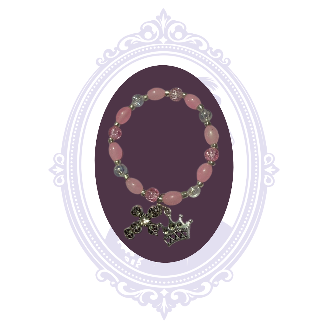 Full view of pink and clear beaded stretch bracelet with dangling cross and crown charms.