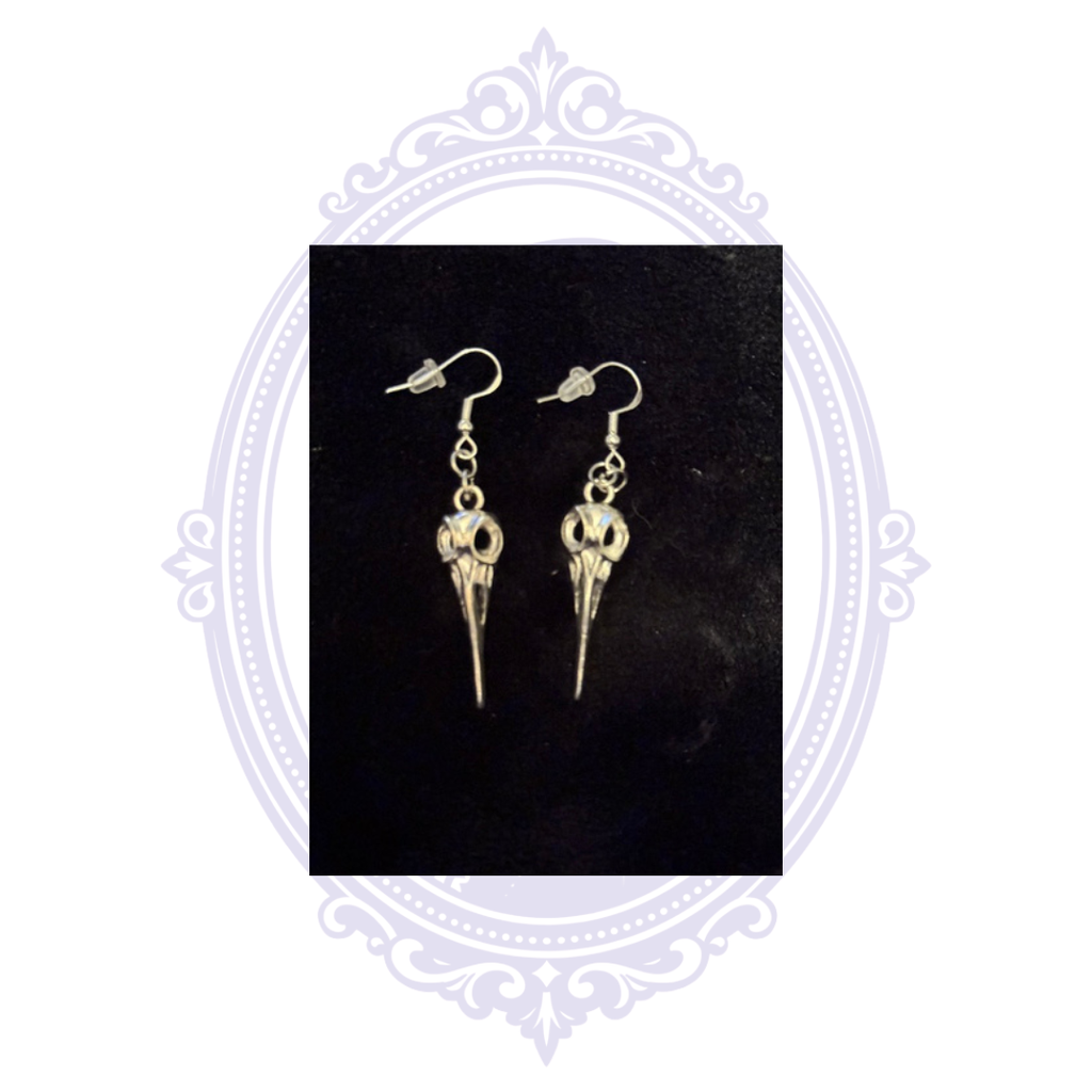 Hand-assembled plague doctor dangle earrings with silver-plated fishhook ear wires and clear silicone backs on a black background.