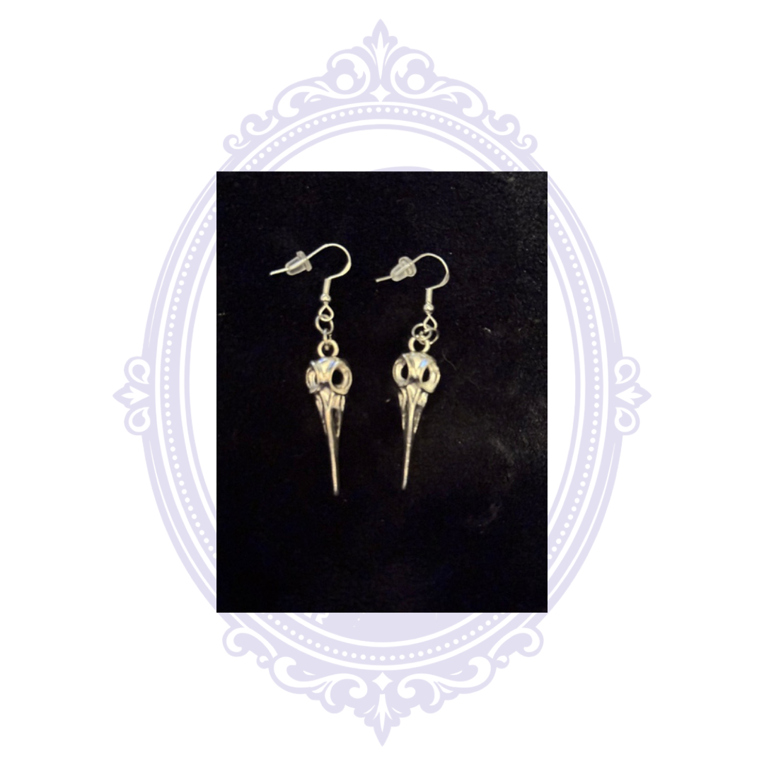 Hand-assembled plague doctor dangle earrings with silver-plated fishhook ear wires and clear silicone backs on a black background.