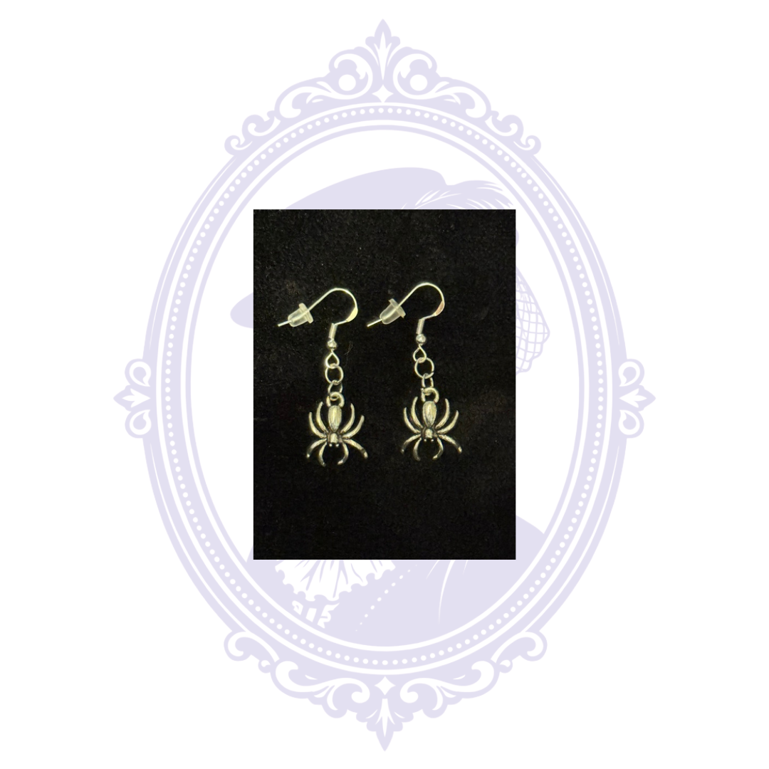 Hand-assembled Cupboard Crafted spider dangle earrings with silver-plated fishhook ear wires and clear silicone backs on a black background.