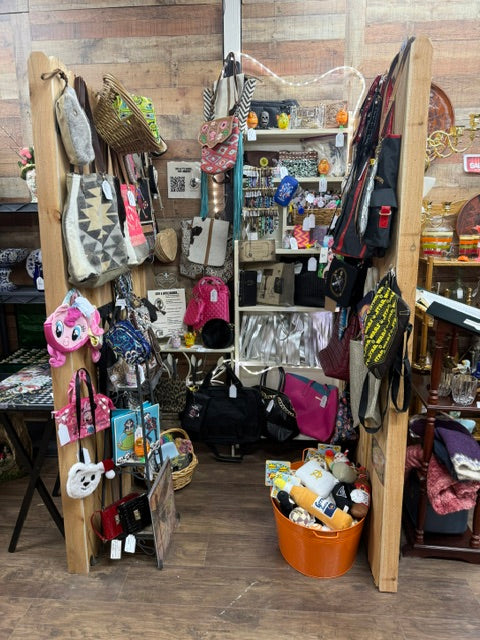 designer dog toys in orange bin with handbags displayed above inside Mrs Bones Curio Cupboard