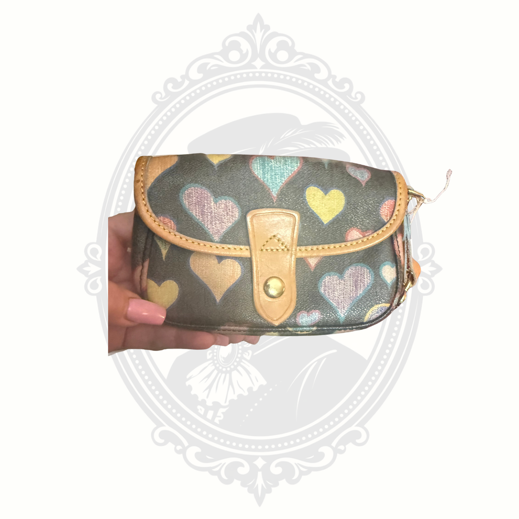 Dooney & Bourke wristlet with multicolor heart print held in hand showing size and snap closure