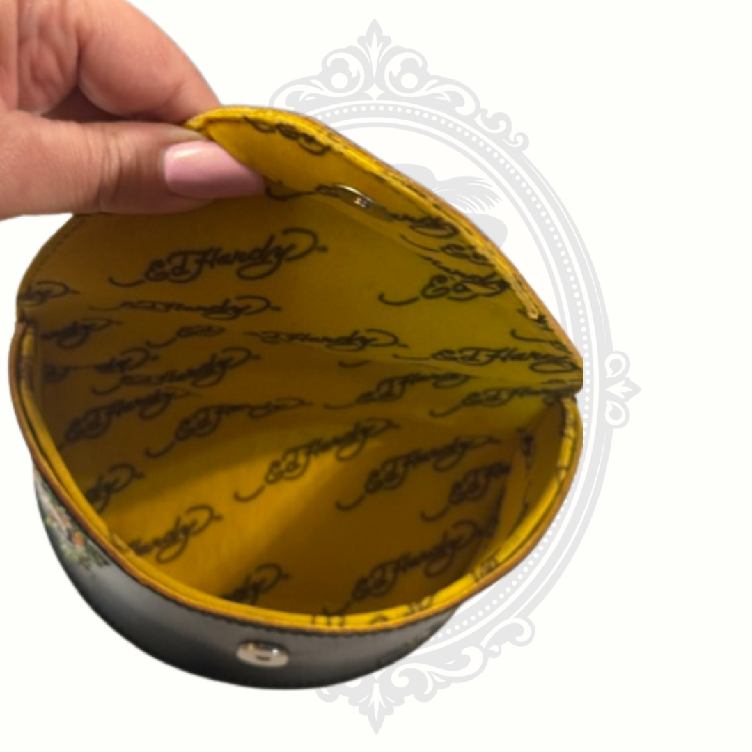 Ed Hardy sunglasses case with yellow fabric lining with black text held by a hand on a white background