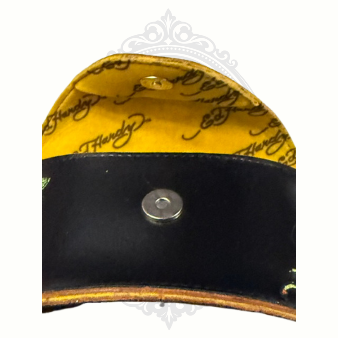 Close-up of a yellow and black pouch with Ed Hardy branding on a white background.