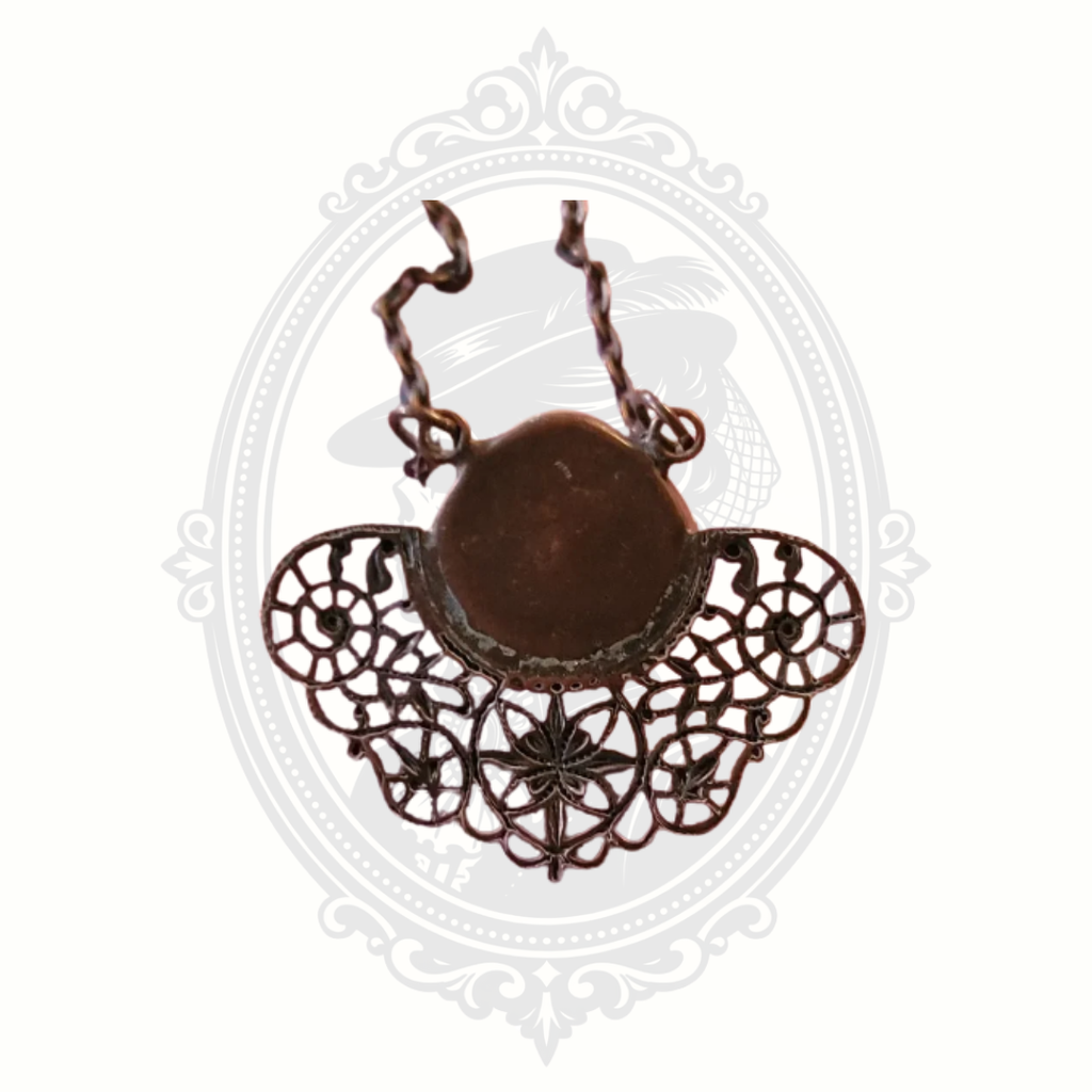 Back view of ornate filigree pendant showing metalwork structure and setting.