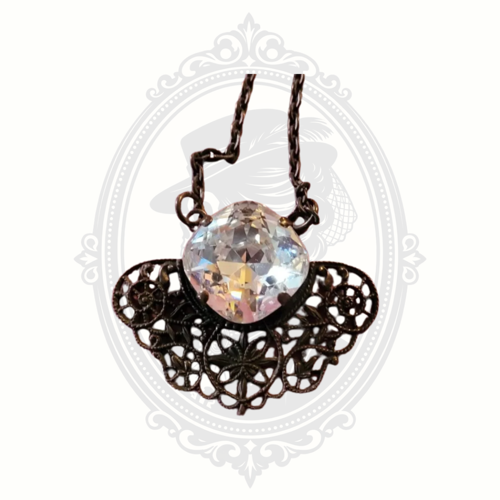 Front view of vintage-style pendant necklace with large faceted crystal and intricate bronze-tone filigree design.