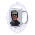 Frankenstein’s Monster blowing a pink bubblegum bubble on a white 15 oz classic horror coffee mug.