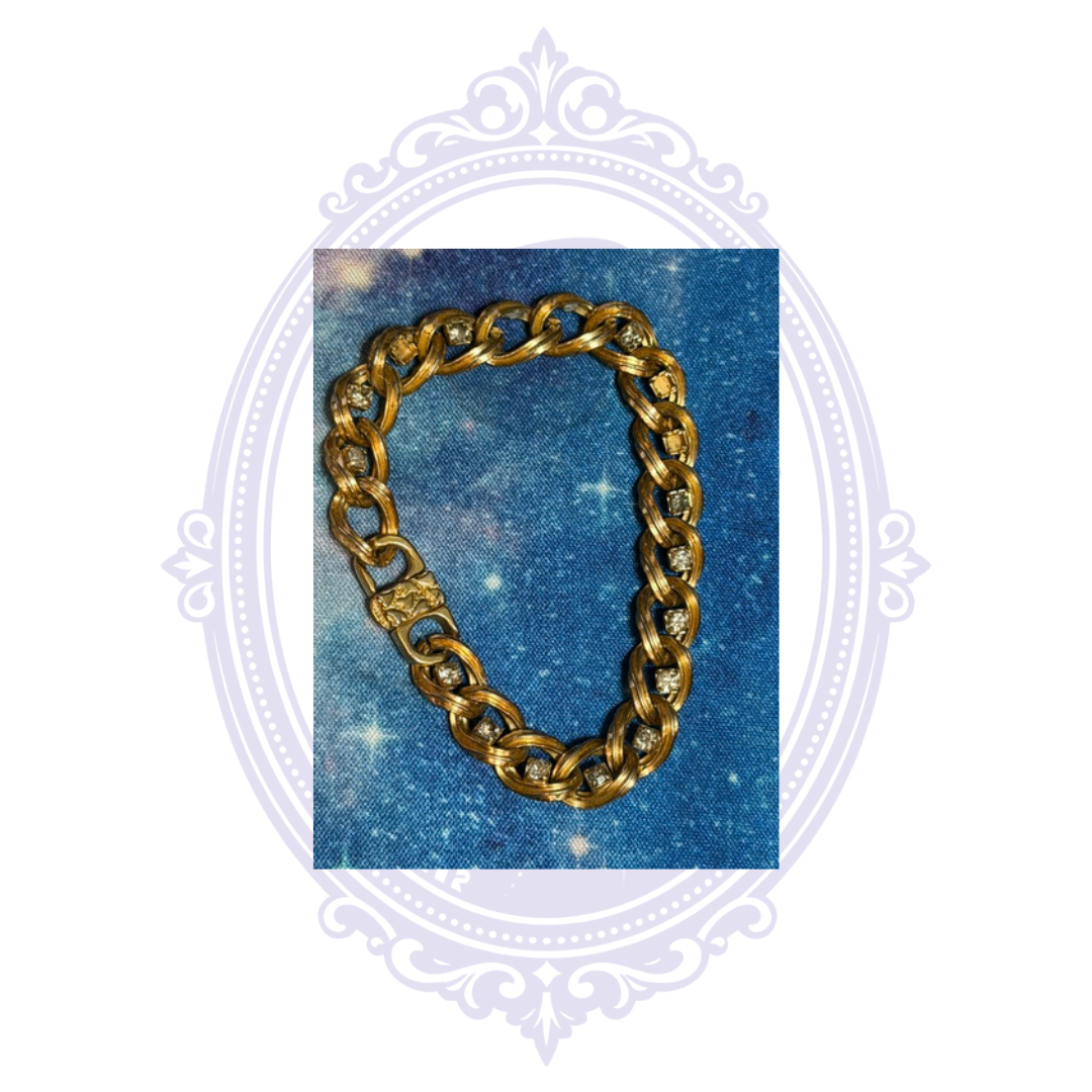 Gold-tone curb chain bracelet with clear rhinestone accents shown in full on background.