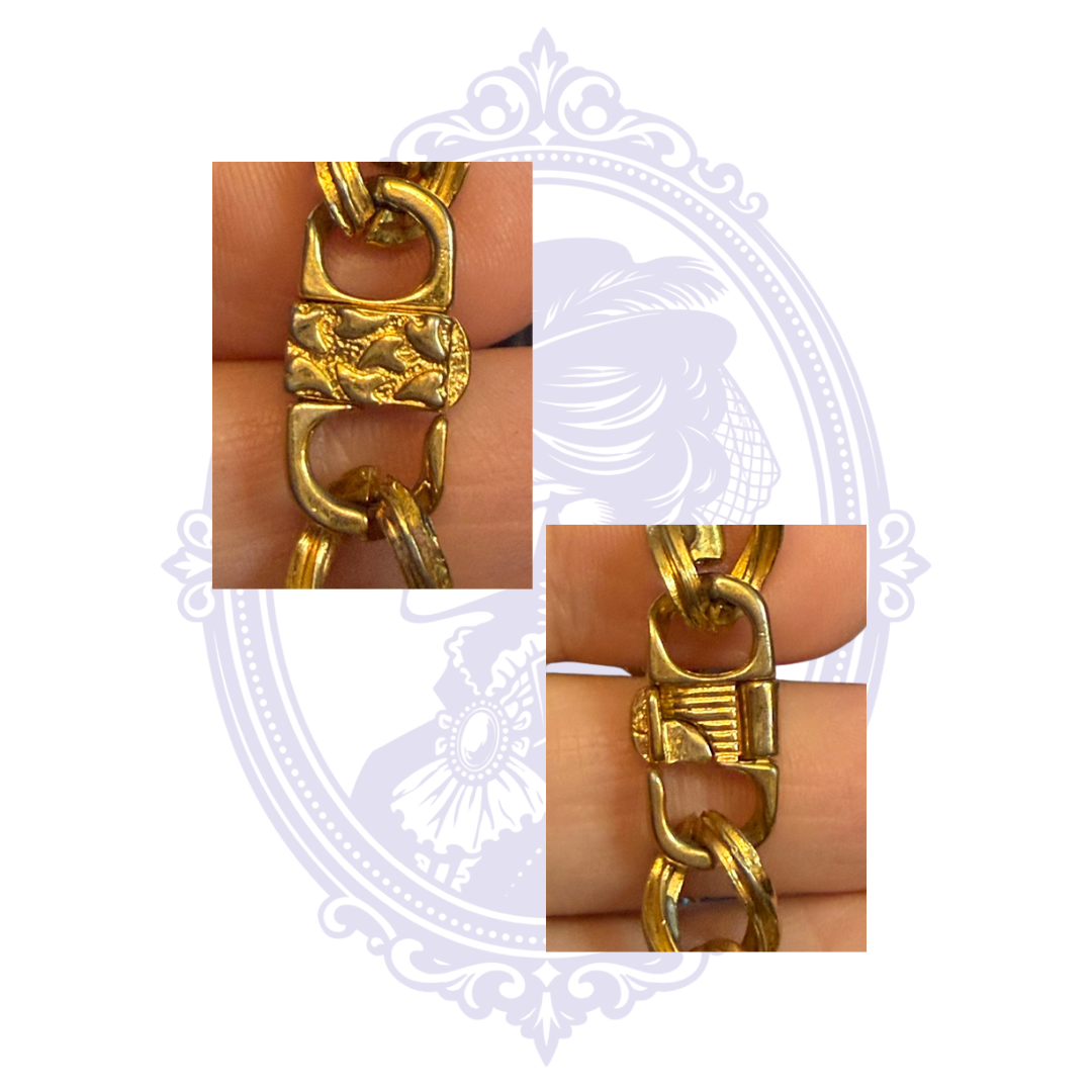 Close-up of the decorative front and back of the clasp on a gold-tone rhinestone curb chain bracelet.