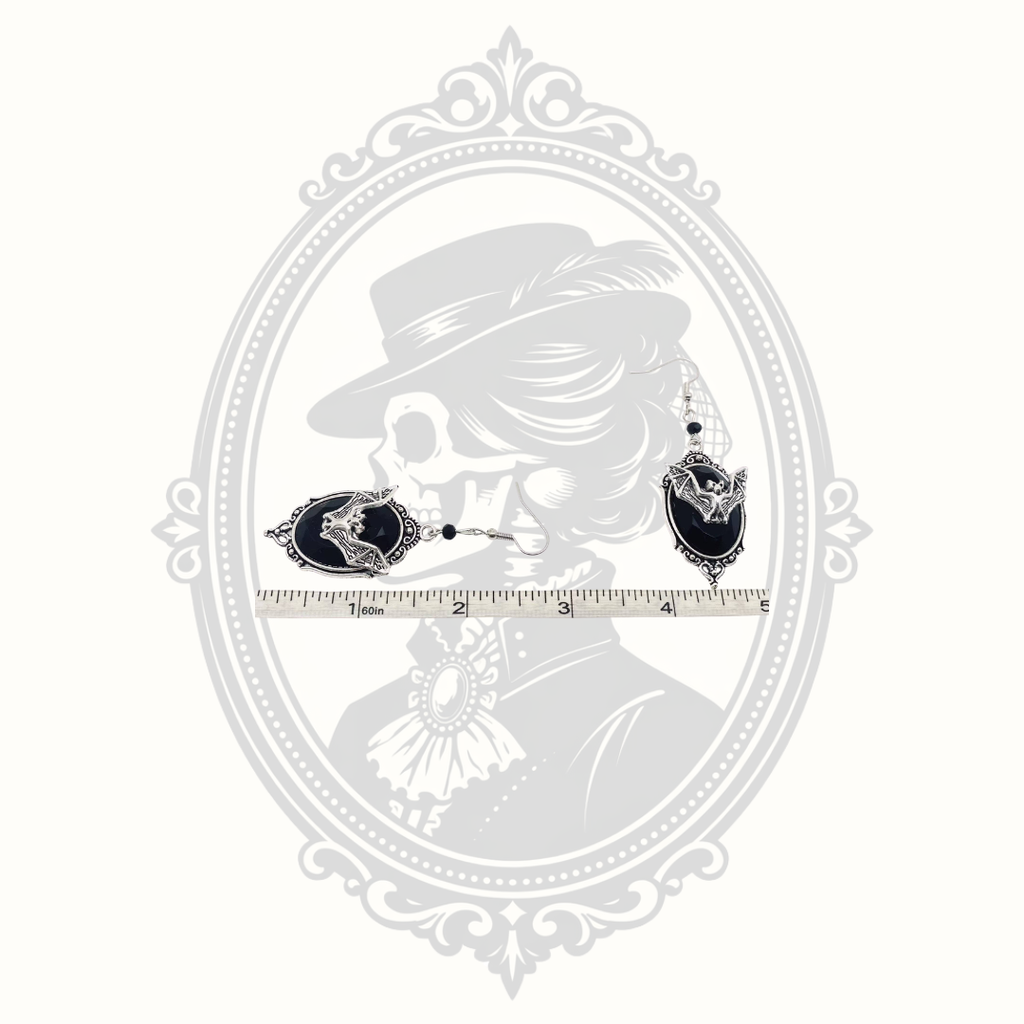 bat cameo drop earrings shown beside ruler for size reference.