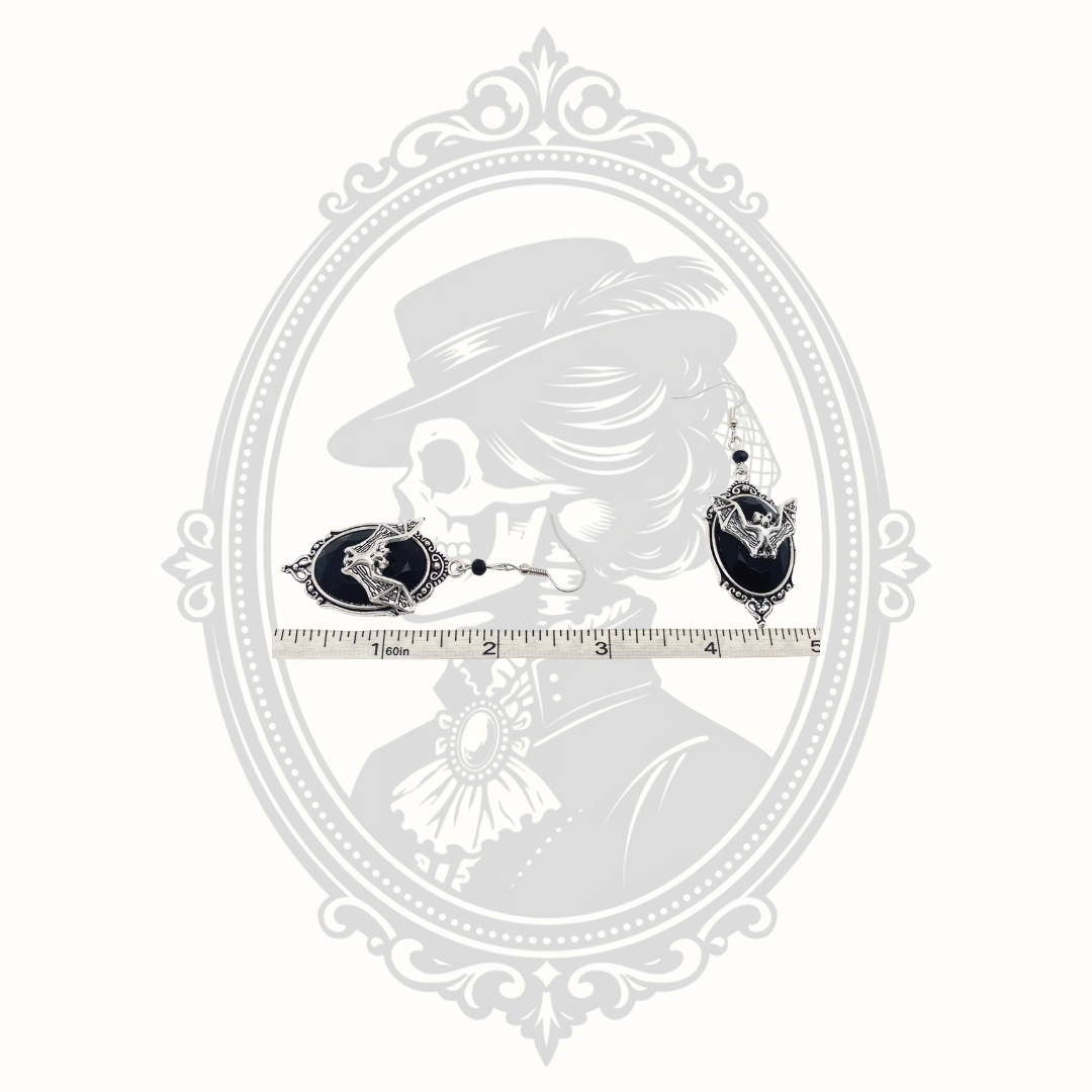 bat cameo drop earrings shown beside ruler for size reference.